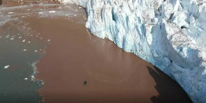 Det brunfargede smeltevannet foran isbreer inneholder næringsrik mat for flere arktiske dyrearter som lever i eller tett på havet. Midt i bildet vises en robot, sendt dit av forskere for å undersøke vannet foran breene.