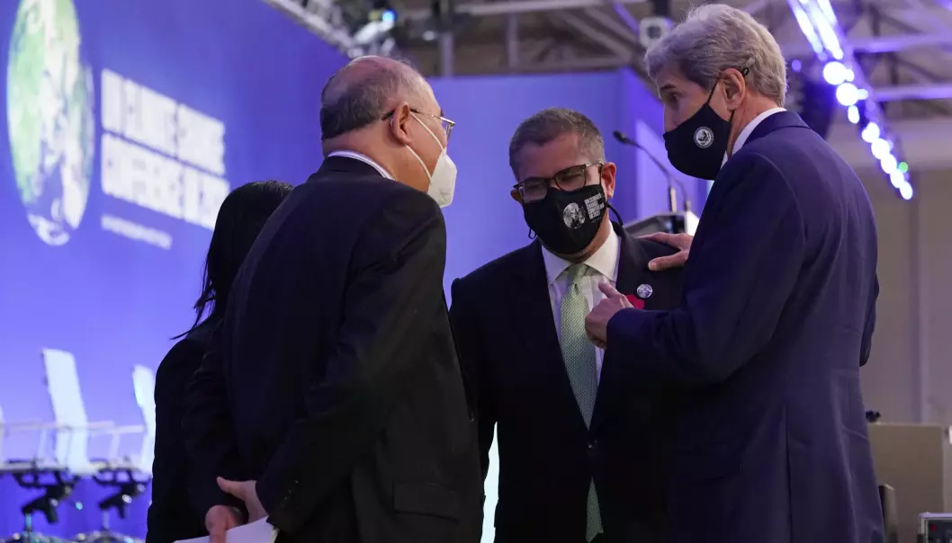 USAs klimautsending John Kerry (t.h.) og hans kinesiske kollega Xie Zhenhua (t.h.) snakker med Glasgow-møtets leder Alok Sharma under den dramatiske sluttfasen av klimatoppmøtet lørdag kveld.