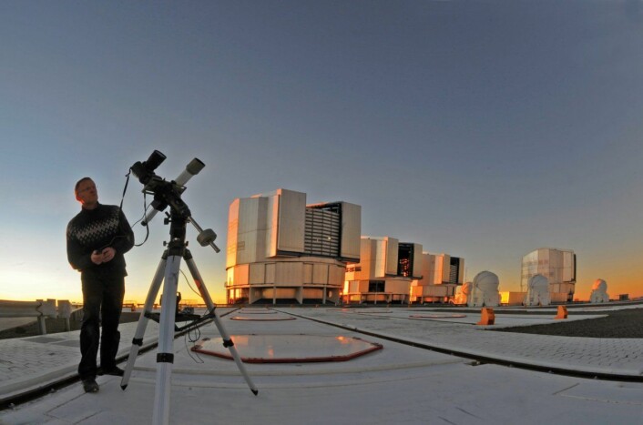 Serge Brunier gjør seg klar til nattens himmelfotografering med sitt speilreflekskamera. Bak sees Very Large Telescope, som er en del av ESOs Paranal-observatorium. (Foto: Serge Brunier/ESO)