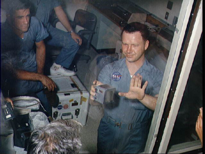 "Da Terry Slezak, en av fototeknikerne på jorda, skulle ta ut filmkassetten av et av Hasselbladkameraene fikk han hånda full av månestøv. Dette var første gang noen andre enn astronautene hadde vært borti støvet, og ingen visste helt hvordan man skulle reagere. På dette bildet sitter fortsatt astronautene i karantene fordi man var redde for at de kunne ha tatt med seg noe utenomjordisk smitte hjem fra verdensrommet. (Foto: NASA)" "Da Terry Slezak, en av fototeknikerne på jorda, skulle ta ut filmkassetten av et av Hasselbladkameraene fikk han hånda full av månestøv. Dette var første gang noen andre enn astronautene hadde vært borti støvet, og ingen visste helt hvordan man skulle reagere. På dette bildet sitter fortsatt astronautene i karantene fordi man var redde for at de kunne ha tatt med seg noe utenomjordisk smitte hjem fra verdensrommet. (Foto: NASA)"
