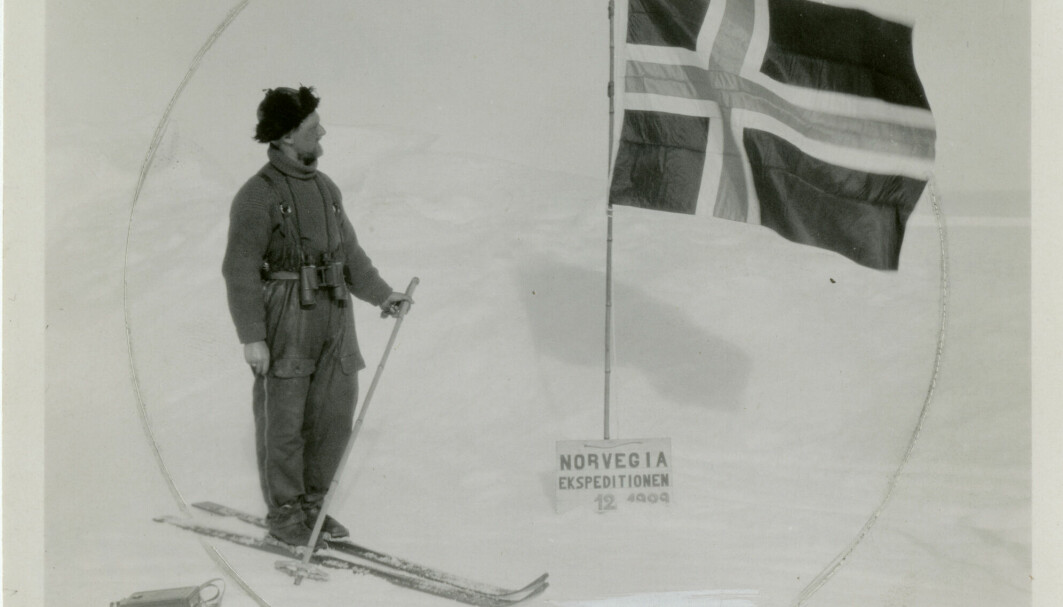 Under den tredje «Norvegia»-ekspedisjonen landet ekspedisjonsleder Hjalmar Riiser-Larsen og Finn Lützow-Holm med fly på det antarktiske fastlandet. Her er Lützow-Holm foran flagget de plantet 22. desember 1929. Foto: Norsk Polarinstitutt