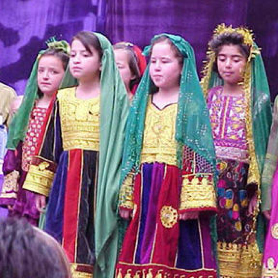 'Afghanske småjenter synger i tradisjonelle klesdrakter. (Foto: USAID, Wikimedia Commons)'