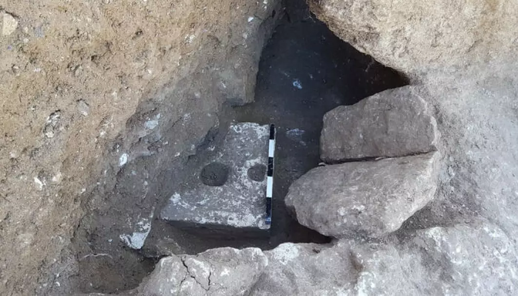 Doen kan skimtes nede i utgravningen, som en hvit stein med hull.