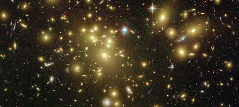 Hvordan ta bilde av mørk materie? Store masser bøyer lyset. Her kikker Hubbleteleskopet igjennom en enorm hop av galakser, mot galakser som ligger bakenfor. Gravitasjonen fra galaksehopen bøyer lyset slik at bildet av galaksene bak blir underlig forstyrret. Hvor sterke slike forstyrrelser blir, kan si en del om hvor mye materie som finnes i galaksehopen. Det er blant annet slike beregninger som hinter om at det må finnes mye mer masse i galaksene enn vi kan se. (Foto: NASA/Hubble Space Telescope)