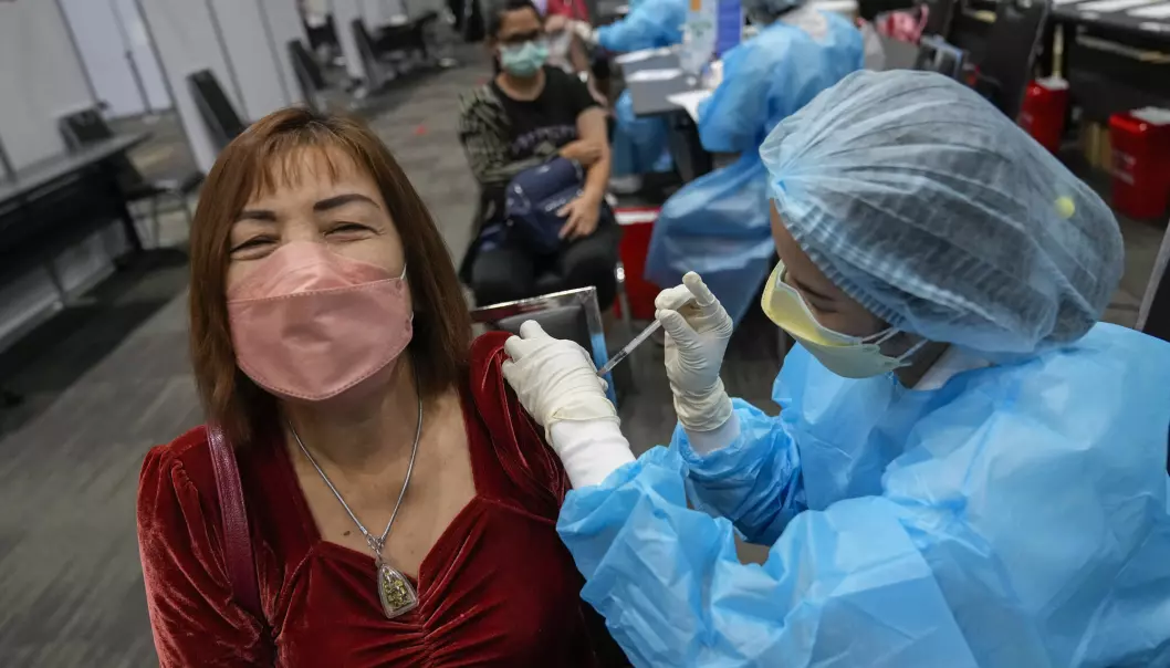 En helsearbeider setter vaksine på et senter i sentrum av Bangkok i Thailand, der vaksineringen har gått tregt sammenlignet med en rekke vestlige land.