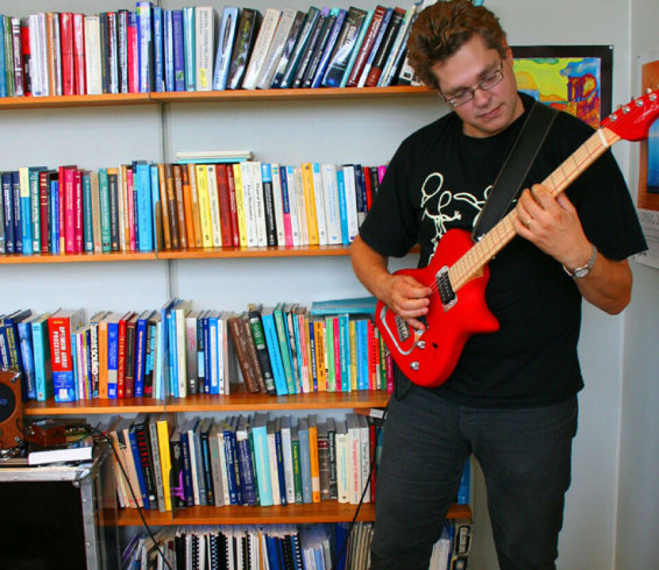 'Musikk og fysikk er uløselig knyttet til hverandre. Alfred Hanssen med sin ergonomiske gitar foran fagbøkene.'