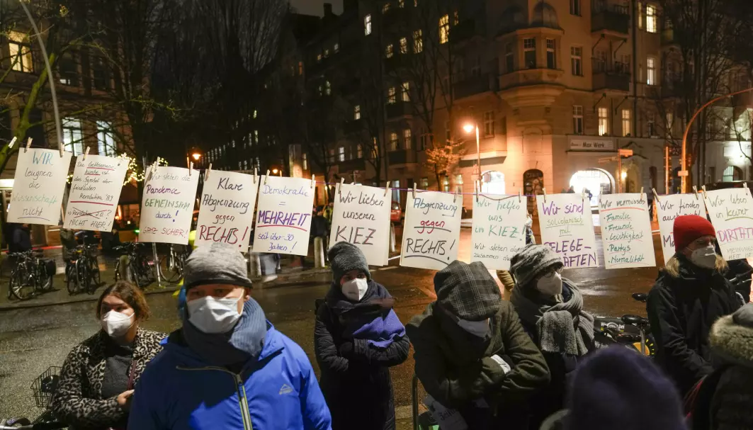Mennesker med munnbind oppfordrer folk til å følge koronarestriksjonene og ikke delta i demonstrasjoner med ytre høyre og konspirasjonsteoretikere i Berlin 24. januar.