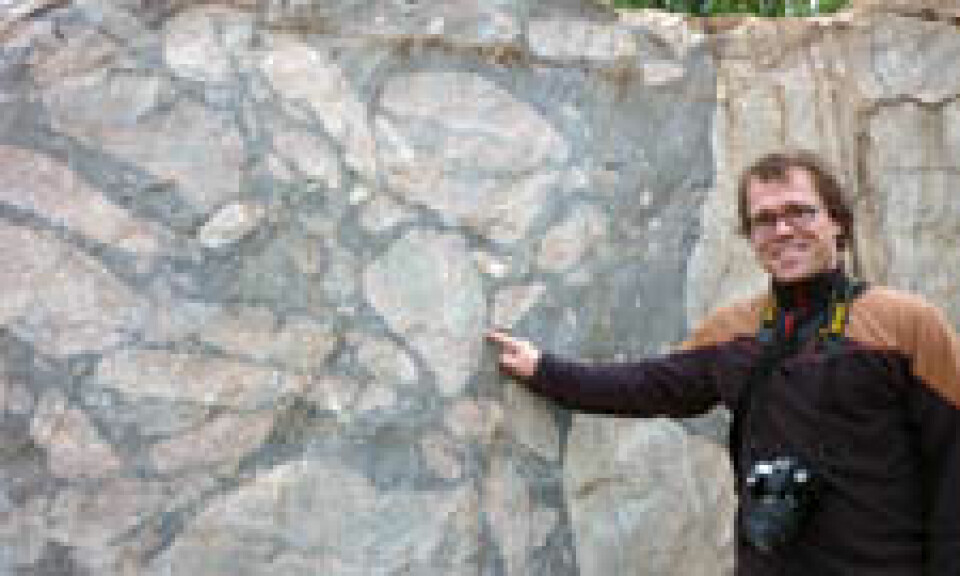 SAMMENSTØT: NGU-forsker Morgan Ganerød ved Vredefort-kratetet i Sør-Afrika, det største bekreftede meteorittkrateret på jorda, dannet for over to milliarder år siden. De fleste flerringformede kratre er ødelagt av erosjon eller platedrift. Ganerød står ved en svært finkornet pseudotachylitt breksje, en bergart som er sønderknust og smeltet under sammenstøtet med meteoritten.