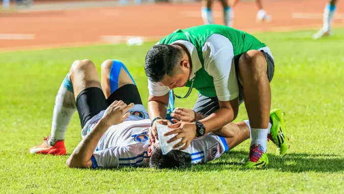 En spiller får førstehjelp etter et kraftig støt mot hodet. Fra kampen Sisaket-Totenham i september 2015.