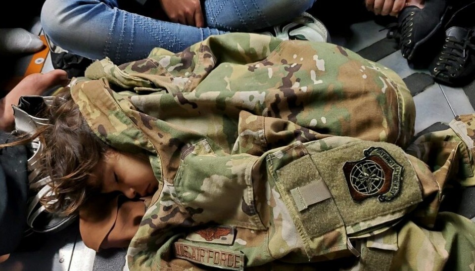 A child from Afghanistan sleeps under an American uniform jacket in the plane that evacuated the family from Kabul in August 2021.