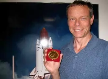 Christer Fuglesang og Nobelmedaljen som han tar med opp i rommet. Foto: ESA.