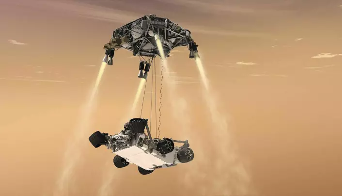 Denne illustrasjonen viser hvordan rakett-kranen løftet roveren ned på Mars-overflaten. Illustrasjonen viser Curiosity-roveren i 2012, men det samme prinsippet ble brukt i 2021.