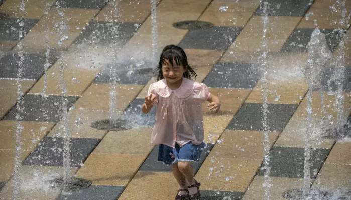 En liten jente avkjøler seg på en ekstremt varm dag i Beijing. Kina opplever den verste hetebølgen på flere tiår, samtidig som styrtregnet satte juni-rekord.