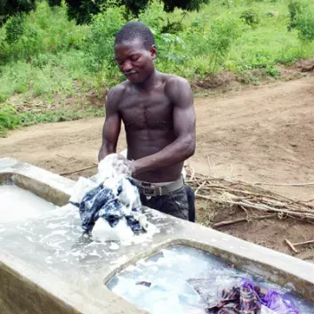 Chimwemwe Douglas vasker klær i de nye vaskene. – Vær så snill å fortell dem at vi trenger flere brønner, sier han. (Foto: Teresa Grøtan)