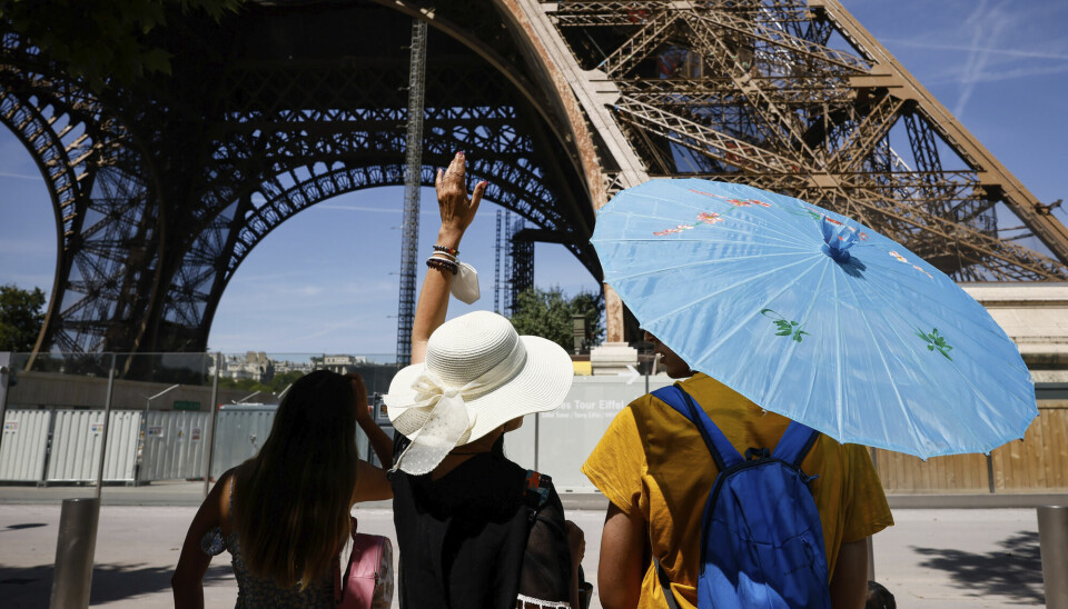 Turister bruker parasoller og hatter for å beskytte seg mot sola i Paris onsdag, på en dag der det ble målt 35 grader.