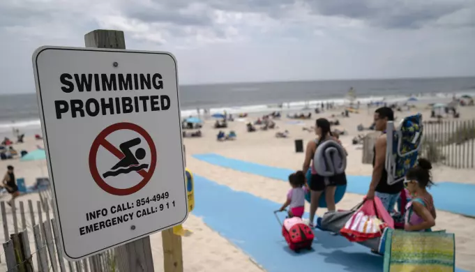 Når haier observeres i nærheten, dukker det midlertidige forbud mot bading. Her har forbudt-skiltet dukket opp på stranda Smith Point County Park på Long Island, der en hai angrep en badevakt 15. juli.