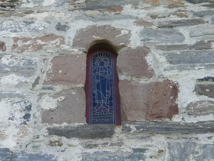 Byggematerialene ble hentet lokalt da de bygde Edøy gamle kirke på 1100-tallet. De røde steinblokkene rundt glassmaleriet består av devonske sandsteiner.