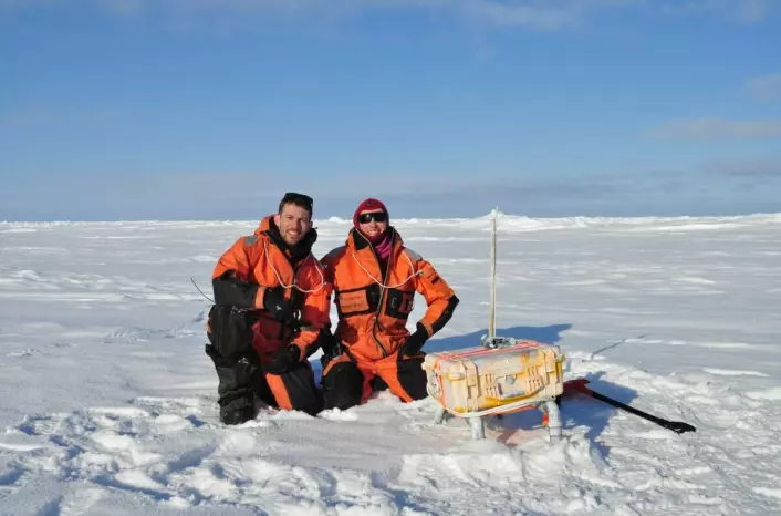 UiT-researchers Polona Itkin and Jack Landy are deploying a sea ice mass balance buoy in the Arctic to record ice thickness.