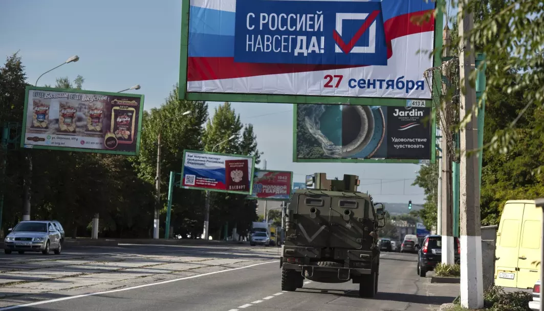 Et militærkjøretøy passerer en plakat med påskriften «Med Russland, alltid!» i forkant av folkeavstemningen i Luhansk. Fredag innlemmes fylket i Russland.