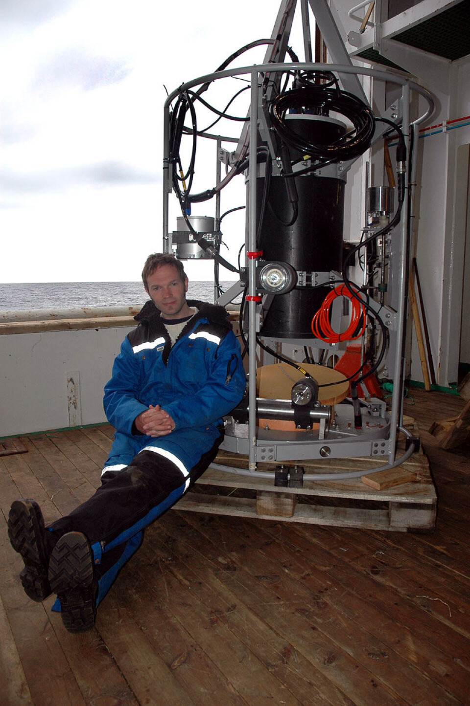 'Georg Skaret sammenligner stereobilder av krillen med ekkogrammer for å få bedre mengdemål av arten. To fotoapparater som tar stereobilder og ekkoloddet er montert på plattformen like bak ham. (Foto: Kjartan Mæstad).'