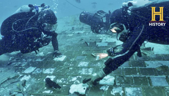 Dykkere inspiserer et stykke av romferja Challenger som de fant på havbunnen utenfor Florida.