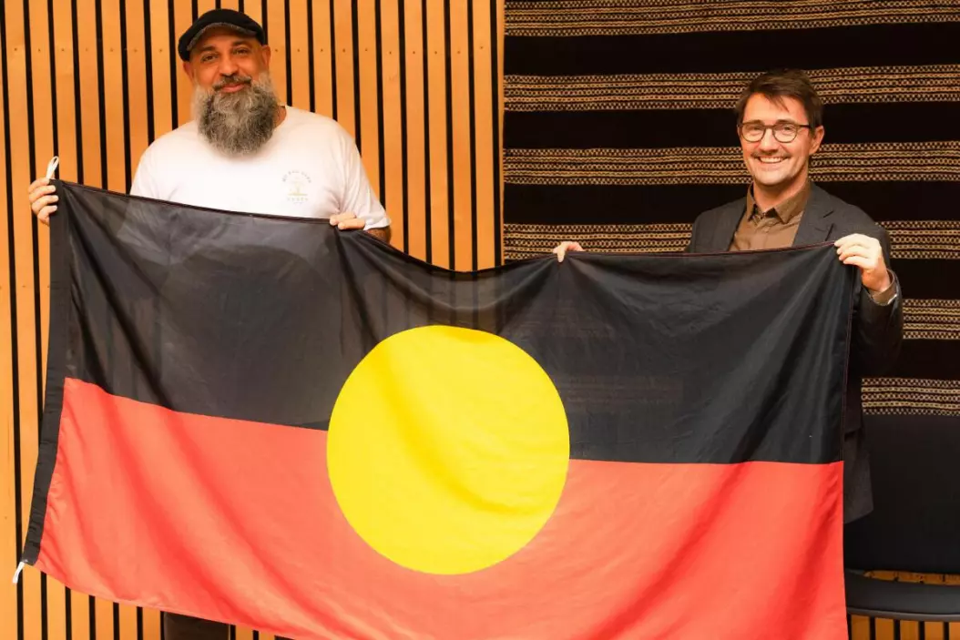 Jade Kennedy gifts the Aboriginal flag from Australia to Torjer Olsen, head of the Center for Sami Studies at UiT. 