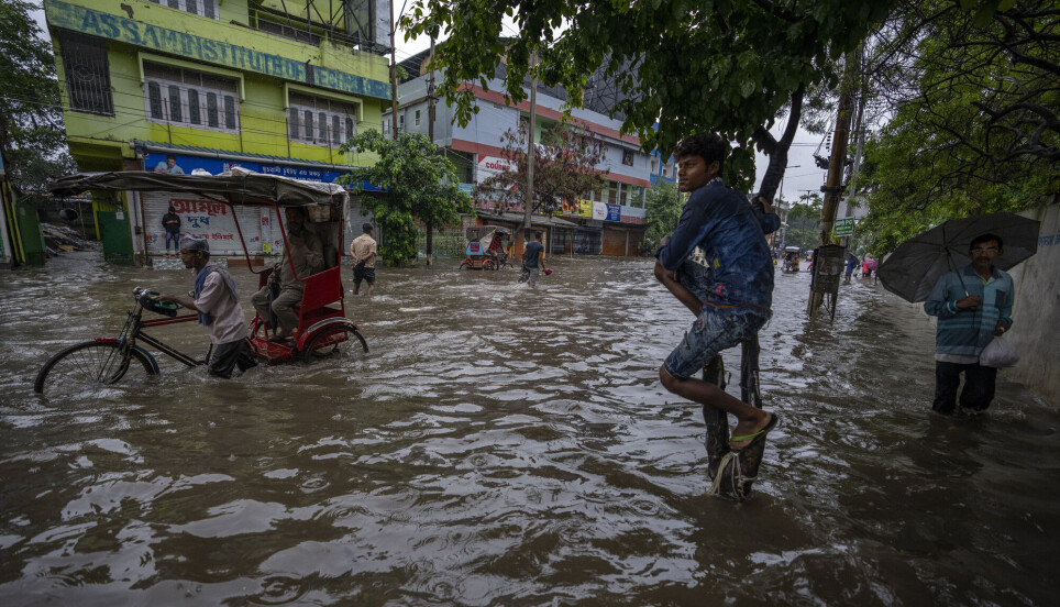 Folk vasser gjennom en oversvømmet vei etter kraftig regn i Guwahati i den indiske delstaten Assam i India i juni. Kraftigere regn og flom er en av virkningene av klimaendringene.