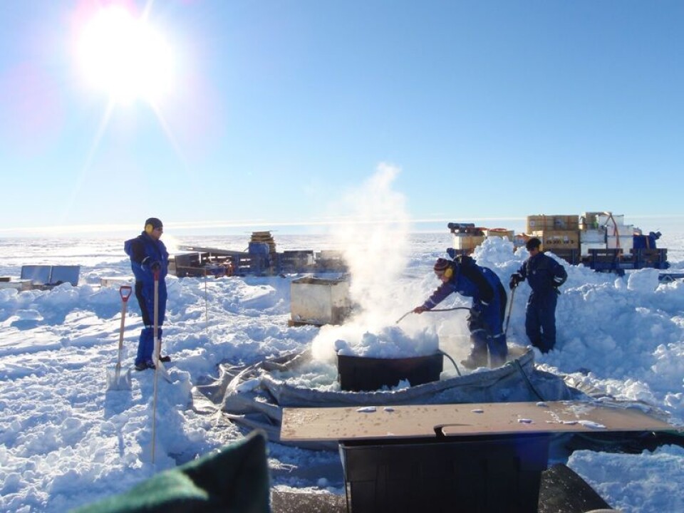 Smelting av snø er første stadiet i smelteboring gjennom is. Her tar Ole Anders og Per Gunnar en pause i snøspaingen, mens Tore spruter varmt vann i smeltekaret. Etterhvert fylles bassenget som rommer 3000 l vann. (Foto: Lars H. Smedsrud)