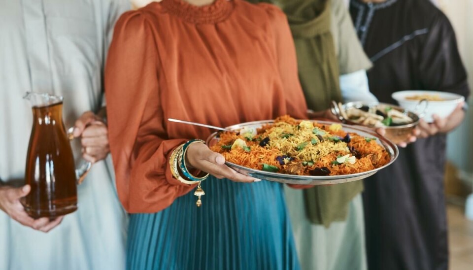 Personer i muslimske drakter med mat på fat.