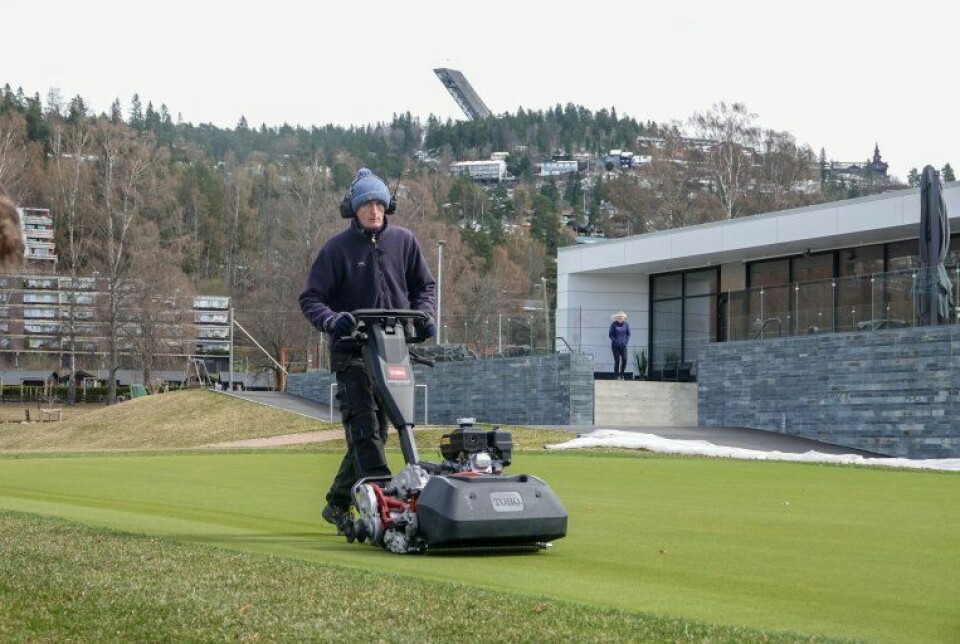 Første klipping av treningsgreenen ved Oslo Golfklubb fredag 30.april. Snøen ligger fortsatt i åsen opp mot Holmenkollen.