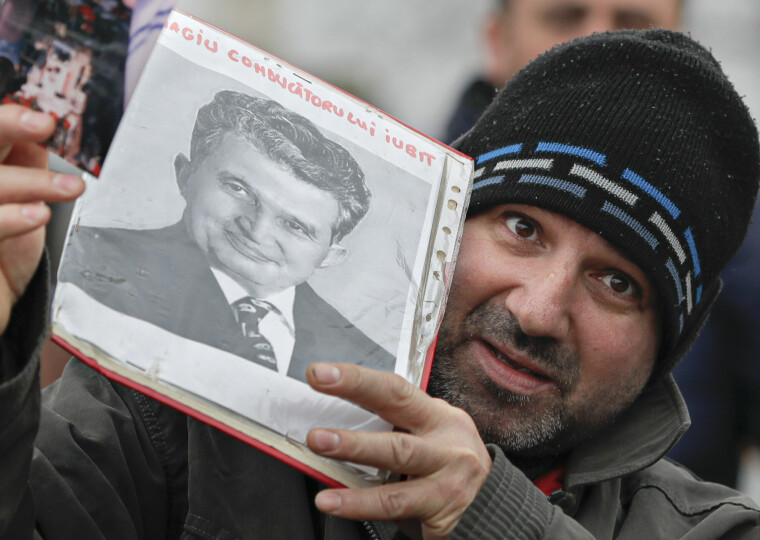 «Hyllest til vår elskede leder», står det på bildet en mann holder opp av den gamle diktatoren. Fortsatt finnes det folk i Romania som ønsker diktaturet tilbake.