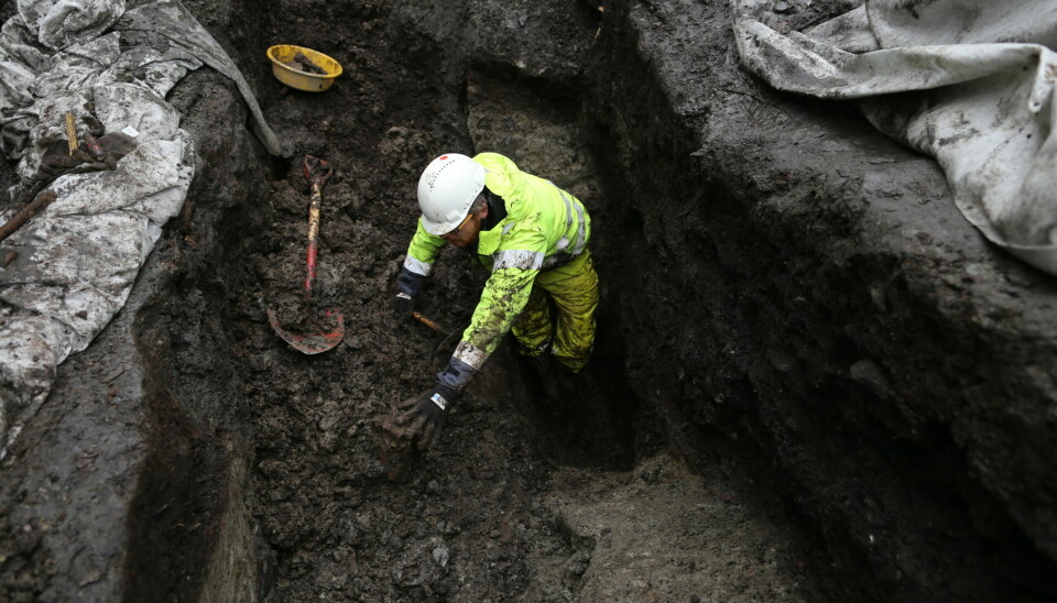 Arkeolog Dag-Øyvind Engtrø Solem i arbeid i gropa hvor spillebrikken ble funnet, nær fire meter under det som er dagens overflate.