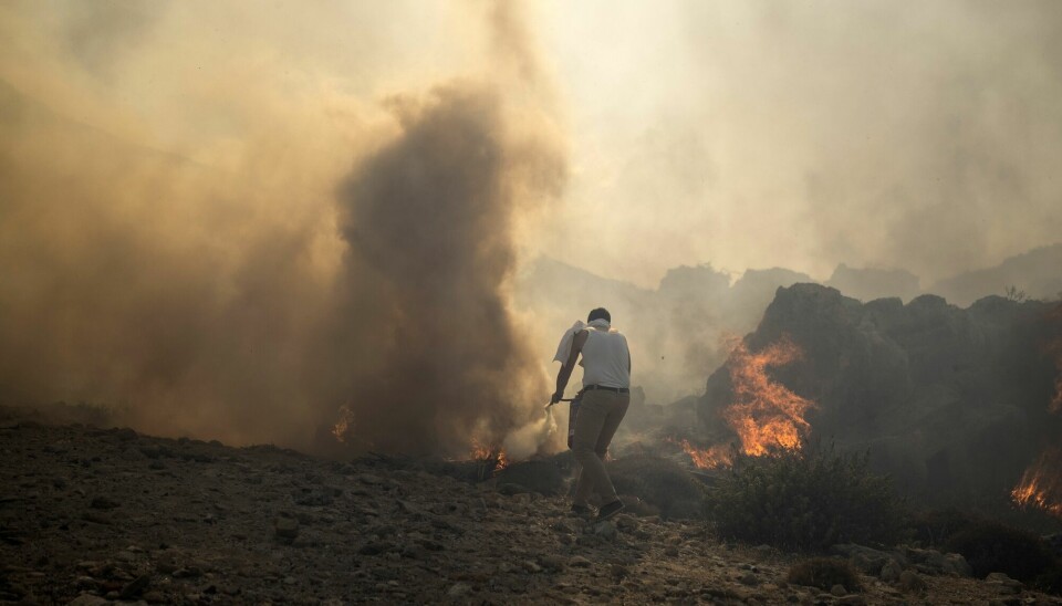 En mann forsøker å slukke en brann i nærheten av Lindos på Rhodos. Sommerens intense hetebølger har økt skogbrannfaren i Hellas og andre land i Sør-Europa.