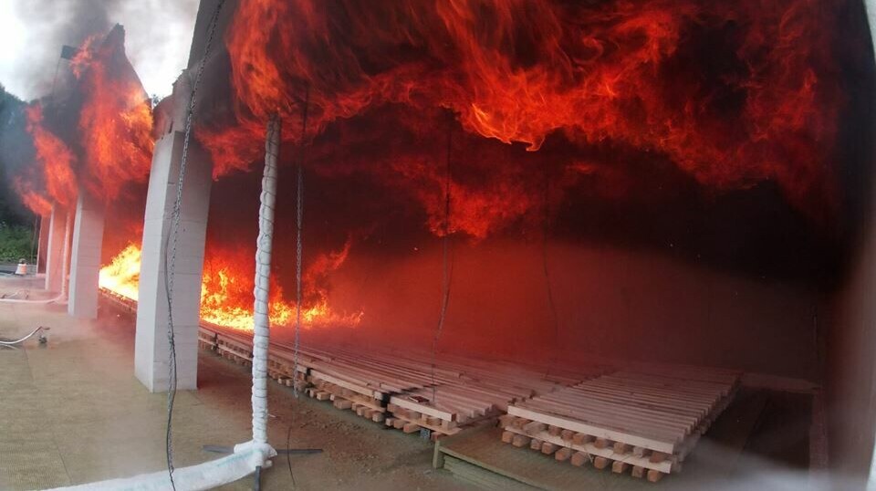 The fire spreads along the hardwood ceiling.  In this experiment, the back wall is covered with plasterboard.