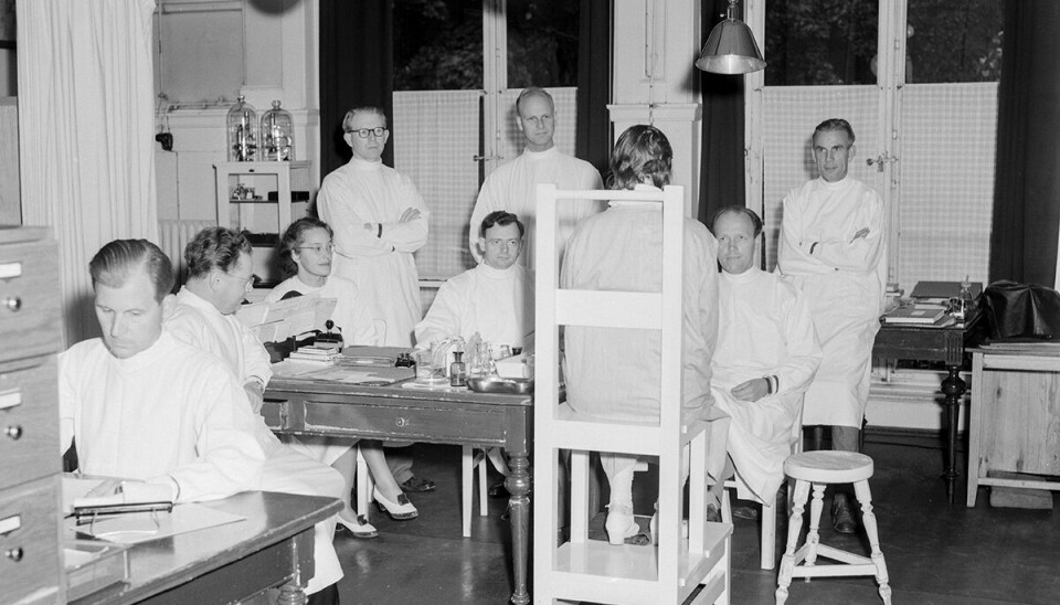 Leger med en pasient på Hudavdelingen, 1951. Stolen pasienten sitter på finnes fortsatt på Rikshospitalet i dag.