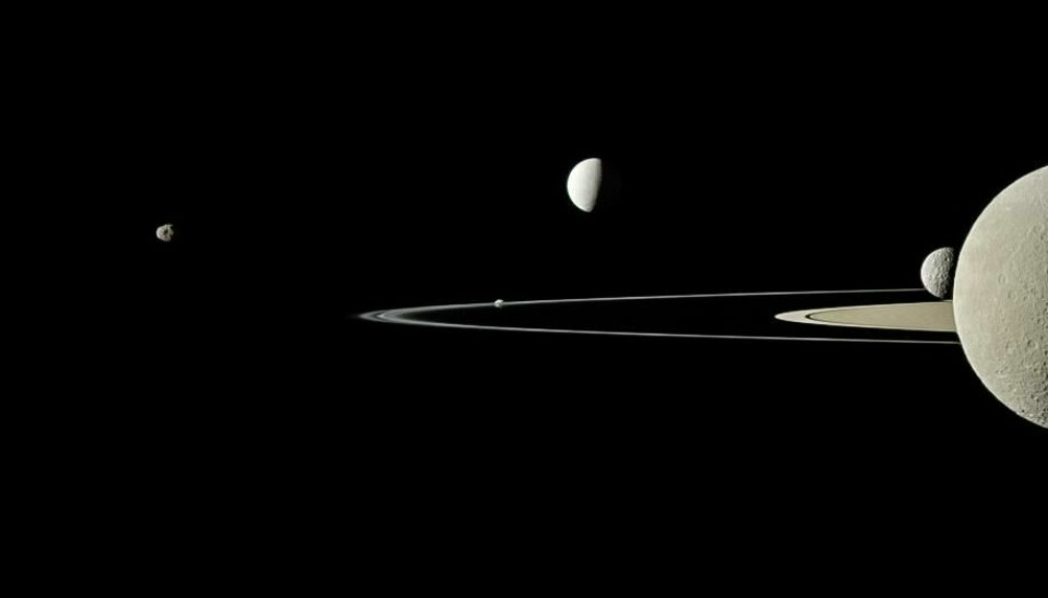 Fem av Saturns måner fanget i det samme bildet av Cassini. Den halve månen til høyre i bildet er Rhea, og Mimas er rett bak denne månen. Du kan se Saturns ringer i bakgrunnen.