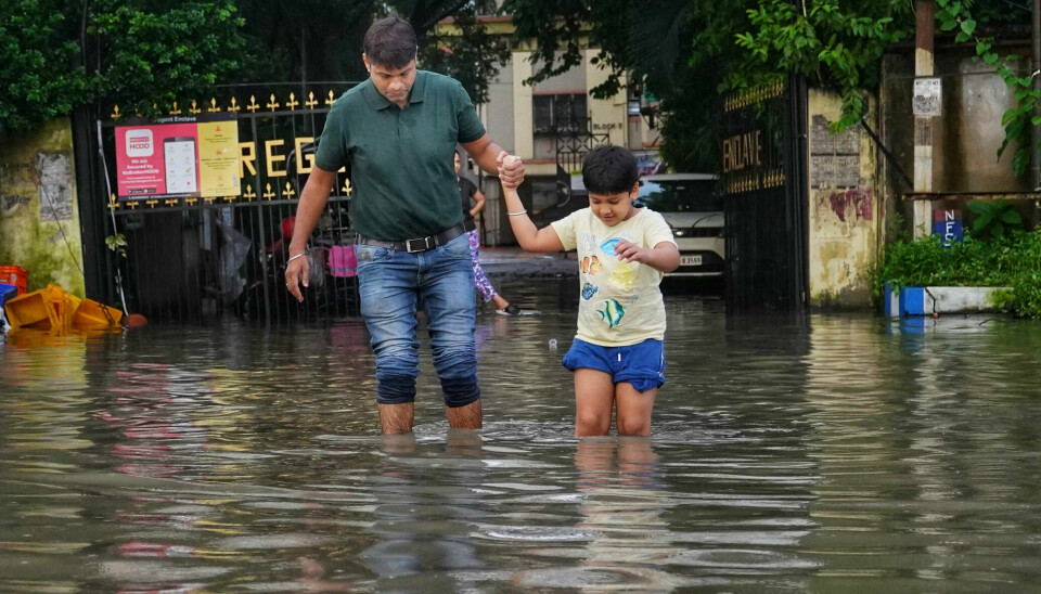 Mann og barn går i oversvømt gate.