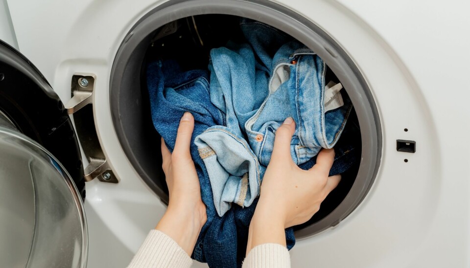 To par jeans blir lagt inn i en vaskemaskin.