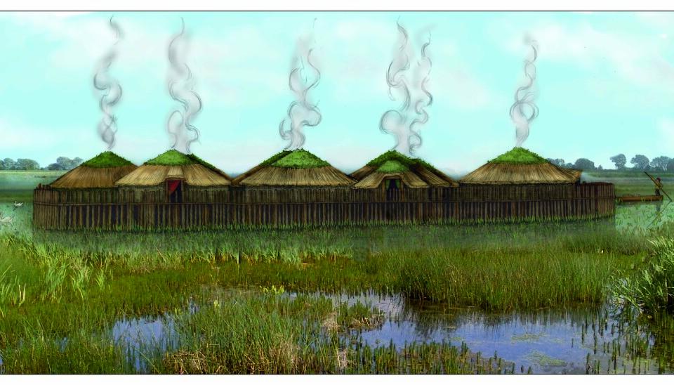 En klynge runde hus med stråtak, bak et høyt gjerde av spisse stokker. Husene står i grunt vann med mye vegetasjon.