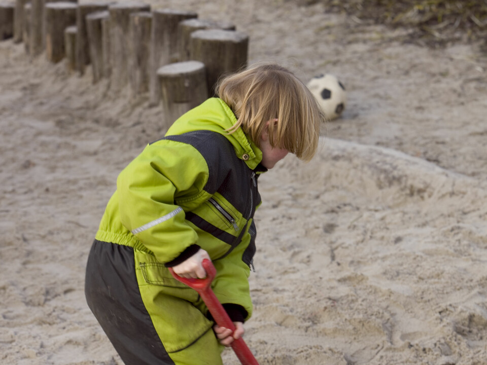 Bilde av et barn som graver i sand i barnehage.
