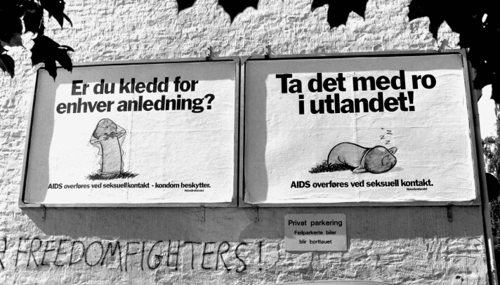 Svart-hvitt bilde. To plakater på murvegg viser tegninger av kondomer, med tekstene: 'Er du kledd for enhver anledning?' og 'Ta det med ro i utlandet'.