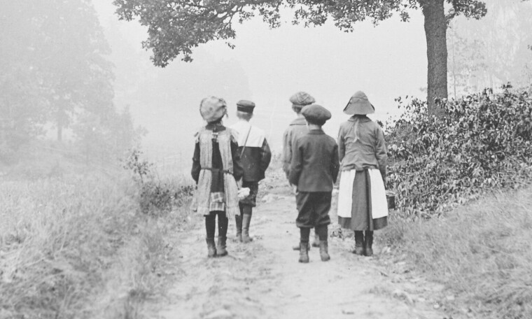 Bildet viser fem barn med ryggen til.
