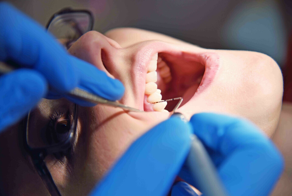 Bilde av åpen munn der tenner blir undersøkt av tannlegen.
