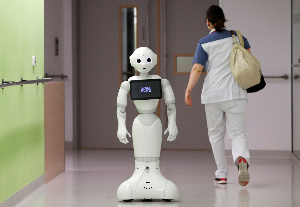 Pepper har ikke blitt noen suksess på sykehjem. En hvit robot med et enkelt fjes og armer, kjører på hjul forbi en sykepleier i en gang.