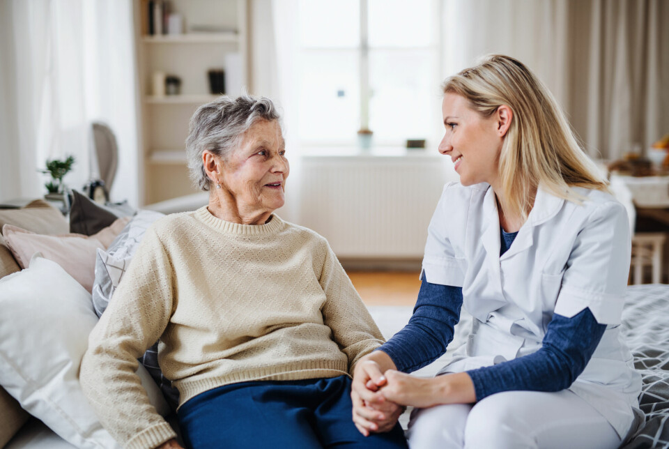Helsearbeider snakker med eldre kvinne