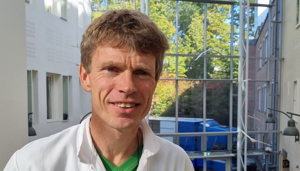Det er fortsatt et ubesvart spørsmål om sykdommen kan komme tilbake etter CAR-T behandling eller om dette er en kur, sier Øyvind Molberg, professor og lege ved Oslo universitetssykehus Rikshospitalet. Mann smiler til kameraet i hvit legefrakk i et sykeusmiljø.