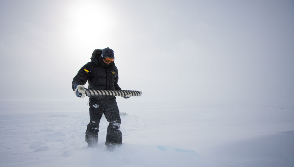 I isen ligger klimahistorien vår. En forsker står ute i snøstorm og holder en iskjerne.