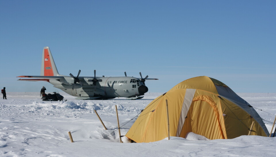 Forskerne bor i telt, og et fly kommer en gang i måneden. Et lasteskip i bakgrunn, med et telt foran. Alt er dekt i snø.
