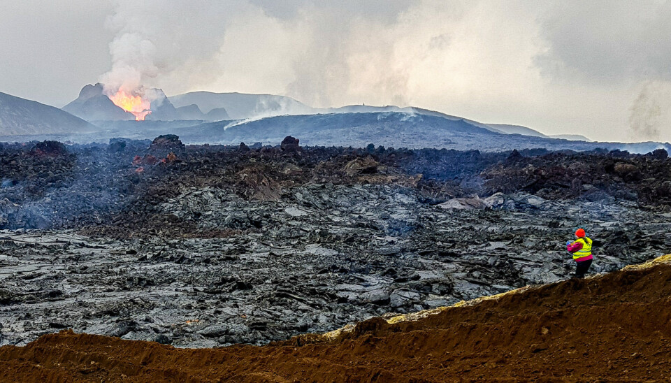 20. mai 2021. Fjóla Guðrún Sigtryggsdóttir undersøker lavafeltet oppstrøms for demningene. Fagradalsfjall-vulkanen i bakgrunnen. 20. mai 2021. Fjóla Guðrún Sigtryggsdóttir undersøker lavafeltet oppstrøms for demningene. Fagradalsfjall-vulkanen i bakgrunnen