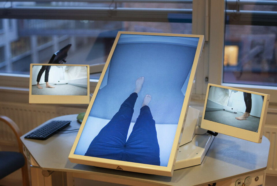The video of two intact legs is displayed on a large monitor in front of the patient.
